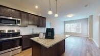 Located at 60 Beard Mill in Shelton, Connecticut, this single-floor residence offers a well-designed layout with contemporary finishes throughout. The kitchen serves as a central highlight, showcasing rich dark cabinetry, light granite countertops, a center island with pendant lighting, and a full suite of stainless steel appliances including a refrigerator, range, microwave, and dishwasher. The kitchen flows naturally into an open living area, which benefits from large windows that invite generous natural light and offer views of the surrounding neighborhood. Warm wood-style flooring runs consistently throughout the home, creating a cohesive and inviting atmosphere. The bedrooms are comfortably sized, with large windows and dedicated closet space providing both comfort and practicality. The bathrooms are finished with wood-style flooring, granite-topped vanities, and clean white fixtures, including a full tub-shower combination. Neutral wall tones and crisp white trim complement every room, lending the space a clean, modern aesthetic. The overall layout is functional and efficiently organized, making this a well-appointed residence suitable for a variety of living needs.