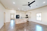 Located at 5241 Rue de Chateau in Alexandria, Louisiana, this single-story, 2-bedroom, 2-bathroom home offers a well-designed layout with consistent finishes throughout. Polished concrete floors run across the living areas and bedrooms, providing a sleek, low-maintenance aesthetic that ties the home together. The kitchen is a highlight, featuring white shaker-style cabinetry extending to the ceiling, granite countertops, black appliances, recessed lighting, and a large island with a striking exposed brick base — a distinctive architectural detail that adds warmth and character. Crown molding accents the main living area, which receives abundant natural light through multiple windows and includes a ceiling fan and direct access to the exterior. Both bedrooms are comfortably sized, each with ceiling fans and natural light from exterior-facing windows. The bathrooms are finished with white cabinetry and granite-top vanities, maintaining the home's clean, cohesive style. A dedicated closet with built-in shelving, a laundry area, and a hallway add practical functionality. The attached garage is spacious and includes an automatic opener and interior access. Outside, a wood-fenced backyard provides privacy along the brick exterior of the home.