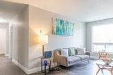 Located at 405 Sidney St in Quinte West, Ontario, this single-floor, two-bedroom, one-bathroom unit offers a well-organized layout that maximizes its compact footprint. The interior is finished with hardwood-style flooring throughout the main living areas, neutral grey-toned walls, and white trim, creating a clean and cohesive aesthetic.

The central hallway connects all rooms efficiently, with a dedicated closet providing additional storage. The living area benefits from natural light through windows that overlook greenery outside. The galley-style kitchen features white shaker cabinetry with brushed nickel hardware, marble-look countertops, a stainless steel refrigerator, and a coil-top range, all set atop light grey tile flooring — a practical and attractive space for everyday cooking.

The primary bedroom accommodates a full-sized bed comfortably and includes a built-in sliding door wardrobe with ample storage. A window allows natural light to fill the room. The second bedroom, also naturally lit with an outdoor window view, offers a cozy and functional space. The bathroom is finished in neutral grey tones and includes a full bathtub with a shower combination. Throughout, the unit maintains a bright, tidy, and functional character.