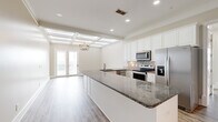 Located at 820 N Thompson Ln in Murfreesboro, Tennessee, this well-appointed single-story home offers four bedrooms and two bathrooms with thoughtfully designed living spaces. The heart of the home is a stunning kitchen featuring an expansive granite island, crisp white cabinetry, a stone tile backsplash, stainless steel appliances, and recessed lighting. The kitchen flows seamlessly toward French doors that invite natural light and outdoor views, while a decorative pendant chandelier adds a refined touch. Distinctive coffered ceilings elevate the open living area, lending architectural character and a sense of spaciousness. The generously sized primary bedroom showcases elegant coffered ceiling details, warm hardwood-style flooring, and access to a walk-in closet with built-in shelving. The primary bathroom impresses with a long granite-topped vanity, tile flooring, an arched window with plantation shutters, and a separate shower area. Secondary bedrooms are finished with plush carpet and tray ceilings accented by crown molding and ceiling fans. A clean, bright secondary bathroom includes a full tub-shower combination. Throughout the home, neutral tones, quality finishes, and consistent design details create a cohesive and inviting atmosphere.