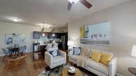 This single-story residence is thoughtfully designed with an open-concept layout that seamlessly connects the living area to the kitchen. The living room features rich wood-style flooring, a ceiling fan, and large windows that invite abundant natural light while offering exterior views. Coastal-inspired décor, including nautical artwork and a mix of neutral and accent tones, creates a relaxed yet polished atmosphere throughout.

The kitchen is well-equipped with dark espresso cabinetry, granite-style countertops, stainless steel appliances including a refrigerator, range, microwave, and dishwasher, and a convenient breakfast bar for casual dining. A dedicated laundry area houses a full-size side-by-side washer and dryer with overhead shelving for storage.

The primary bedroom offers plush carpeting, a ceiling fan, and ample space, while the second bedroom provides a similarly comfortable retreat with coordinating finishes. Both bathrooms feature dark vanity cabinetry with stone-look countertops, a single sink, and a shower-tub combination. Wood-style flooring extends through the bathrooms, maintaining a cohesive aesthetic across the entire residence.