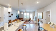 Located along RM-620 in Austin, TX, this thoughtfully designed one-bedroom, one-bathroom residence offers a cohesive open-concept layout connecting the kitchen, dining, and living areas. Light wood-tone flooring runs throughout, lending a warm, unified aesthetic to the entire space.

The kitchen is a standout feature, showcasing crisp white cabinetry, stainless steel appliances, a dark tile backsplash, quartz countertops, and a center island with pendant lighting and bar seating — ideal for both cooking and casual dining. Adjacent to the kitchen, the dining area provides a dedicated space for meals, while the bright living room benefits from large windows offering scenic outdoor views and access to a balcony, complemented by a ceiling fan overhead.

The generously sized bedroom is a comfortable retreat with a ceiling fan, ample natural light from large windows, and direct access to the closet. The full bathroom is sleekly designed with white cabinetry, quartz countertops, a glass-enclosed walk-in shower with marble-style tile surround, and wood-look flooring. A spacious walk-in closet connects directly to the bathroom, adding practical storage.

Clean lines, neutral tones, and modern finishes throughout create a polished and functional living environment in this Austin residence.