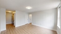 This 2-bedroom, 1-bathroom unit offers a thoughtfully organized single-floor layout with a clean, modern aesthetic throughout. Light wood-tone flooring runs continuously across all rooms, complemented by crisp white walls and trim that create a bright, cohesive feel.

The primary bedroom is the most spacious room in the unit, featuring dual windows with a window-unit air conditioner and baseboard heating, along with a double-door closet that provides generous storage. Views from these windows look out toward an urban cityscape. The second bedroom is more intimate in scale and similarly benefits from natural light, with access to a connecting hallway and additional closet space.

A central hallway connects all rooms efficiently and includes a utility panel. The kitchen, visible from the hallway entry, features white subway tile backsplash and is equipped with an electric range.

The bathroom stands out as a refined highlight of the unit, finished with large-format stone-look tile on both the floors and walls. It includes a soaking tub, a wall-mounted vanity with a modern vessel sink and contemporary faucet, a toilet, and a natural-light window with blinds — all combining to create a spa-like atmosphere. A mirrored medicine cabinet adds functionality.

Overall, the unit presents a clean, renovated interior with consistent finishes throughout.