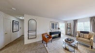 Located at 1 Overton Way in Asheville, NC, this single-floor, 2-bedroom, 2-bathroom residence offers a comfortable and functional layout with a warm, neutral aesthetic throughout. The living room features plush carpeting, natural light from large windows dressed with soft drapes, and generous space for seating arrangements. A secondary living area provides additional flexibility for dining or relaxing. The kitchen is equipped with black appliances—including a range, microwave, and refrigerator—warm wood cabinetry, and dark stone countertops, flowing seamlessly into a tiled dining area with room for a full dining set. The primary bedroom is a spacious retreat with plush carpet, a ceiling fan, ample natural light from large windows, and access to a dedicated closet. The second bedroom also features carpet flooring, a large window with natural light, and its own closet. Both bathrooms are finished with tile flooring, wood-toned vanity cabinetry, and full shower-tub combinations. One bathroom features warm vanity lighting and a large mirror, while the second offers a clean, bright design. Two dedicated closets provide practical storage throughout the residence. The overall ambiance is bright, clean, and inviting—ideal for comfortable everyday living in the heart of Asheville.