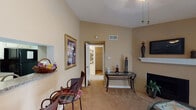Located at 19321 Park Row Dr in Houston, TX, this single-floor residence offers a well-organized layout designed for comfortable everyday living. The living room serves as the central gathering space, featuring vaulted ceilings, a fireplace with a white mantle, and a sliding glass door that allows natural light to fill the room. A ceiling fan adds to the functionality of the space.

The galley-style kitchen is efficiently designed with white cabinetry, granite-patterned countertops, a double sink, black appliances including a refrigerator and dishwasher, and hardwood-style flooring. Ample upper and lower cabinet storage makes this kitchen both practical and organized.

Adjacent to the kitchen, a dedicated dining area provides space for a round glass-top table and chairs, accompanied by a window that brings in additional natural light.

The bedroom is carpeted and offers a comfortable, quiet retreat, with a window fitted with blinds and sufficient space for furnishings. A hallway connects to additional storage areas and interior rooms.

The bathroom features granite-patterned countertops, cream-toned cabinetry, a large mirror, and overhead lighting, maintaining a clean and functional aesthetic consistent throughout the home. Warm, neutral tones unify the interior design across all spaces.