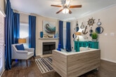 Located at 808 Gladstell St in Conroe, Texas, this single-floor residence offers a thoughtfully designed layout that balances comfort and functionality. Rich dark hardwood flooring flows throughout the main living areas, grounding the open-concept design and providing a warm contrast to the neutral-toned walls.

The living room provides a welcoming gathering space that opens seamlessly toward the kitchen and dining area. The kitchen features a breakfast bar with a marble-style countertop, dark cabinetry, and black appliances, including a range and refrigerator. A dedicated dining nook with a pendant light adds an elegant touch, while an in-unit laundry area adds everyday convenience.

Both bedrooms are carpeted for added comfort and are equipped with ceiling fans. The primary bedroom enjoys natural light from a large window dressed with teal drapes and connects to a well-appointed bathroom. The bathroom showcases an extended vanity with dark espresso cabinetry, a marble-style countertop, a single undermount sink, and a large framed mirror—creating a refined, spa-like feel.

The overall aesthetic throughout the home is cohesive and contemporary, with coastal-inspired accents, crown molding details, and ample storage that make this residence both practical and visually inviting.