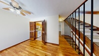 Located at 4780 Nugent Dr in Columbus, Ohio, this multi-floor home offers two bedrooms, two bathrooms, and a well-organized layout distributed evenly across three floors, providing a clear separation of living, sleeping, and utility spaces. The main living area features warm-toned hardwood flooring that extends throughout, complemented by neutral white walls and a ceiling fan that adds both function and character. A set of open stairs with a sleek metal railing connects the floors, contributing to the home's open sightlines. The kitchen is accessible through charming louvered bifold doors and is equipped with wood cabinetry and standard appliances, including a range and over-the-range microwave. A pass-through window connects the kitchen to the adjoining living space, adding a practical touch. The living room includes a sliding glass door with vertical blinds, allowing natural light to filter in. The spacious primary bedroom is carpeted and features a ceiling fan, a sliding glass door opening to a balcony, and a closet with a wood-paneled door. The second bedroom is also carpeted with access to a utility panel. The bathrooms include one with white subway tile wainscoting and an extended countertop, and another with a full tub-shower combination with updated brushed nickel fixtures.