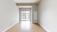 Located at 208 Woolwich St S in Woolwich, Ontario, this well-appointed 2-bedroom, 2-bathroom unit offers a thoughtfully designed open-concept layout finished with contemporary details throughout. Light-toned hardwood flooring flows seamlessly across the entire space, complementing the neutral grey palette on the walls and creating a bright, cohesive atmosphere.

The kitchen is a standout feature, showcasing crisp white shaker-style cabinetry, rich dark granite countertops with a tile backsplash, and a full suite of stainless steel appliances including a refrigerator, range, microwave, and dishwasher. A breakfast bar provides additional counter space and connects the kitchen to the combined dining and living area, which is bathed in natural light from a large sliding glass door leading to the private balcony. The balcony offers serene views of mature evergreen trees and the surrounding landscape.

Both bedrooms are comfortably sized, each featuring windows overlooking the lush treetops, hardwood floors, and ample closet storage — with five closets distributed throughout the unit. The two bathrooms are finished to match the kitchen's aesthetic, with white cabinetry, dark granite vanity tops, and clean tile work. One bathroom features an elegant glass-enclosed corner shower. A dedicated entrance and hallway complete this well-organized, move-in ready home.