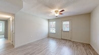 Located at 312 Scott St in Brewton, Alabama, this single-floor home offers a practical and comfortable layout across two bedrooms and a combined kitchen and living area. The living room greets you with light-toned luxury vinyl plank flooring, neutral wall tones, and a ceiling fan with integrated lighting. Large windows allow natural light to flow in, creating a bright and welcoming atmosphere. A paneled front door with a window further enhances the airy feel of the space. The kitchen is equipped with rich, warm-toned cabinetry, a gas range, a full-size refrigerator, and a range hood, all complemented by light countertops and matching vinyl plank flooring. A pendant light fixture adds a finishing touch to the dining area just adjacent to the kitchen. The spacious primary bedroom features plush carpeting, a ceiling fan, and a natural light source through a window with blinds. Both bedrooms include double-door closets with classic six-panel doors, offering generous storage. A dedicated closet space further adds to the home's organizational convenience. Textured ceilings throughout lend a consistent, cohesive character to every room, while the clean, neutral palette makes the entire home feel move-in ready.