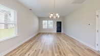 Located at 304 Bedstone Dr in Navassa, NC, this well-appointed two-story home offers a thoughtful layout across two floors. The main level features a bright, open-concept living, dining, and kitchen area bathed in natural light from multiple windows. The kitchen is a standout, showcasing white shaker cabinetry, a subway tile backsplash, light granite countertops, a center island, stainless steel appliances, and recessed lighting. Light wood-tone luxury vinyl plank flooring flows seamlessly throughout both levels, complementing the home's clean, neutral palette. An elegant chandelier anchors both the dining area and the entryway, adding a refined touch. The main floor also includes an attached garage with an automatic opener and an electrical panel. Upstairs, three well-sized bedrooms provide comfortable retreats, including a spacious primary bedroom with a walk-in closet featuring wire shelving. The primary bathroom is equipped with a dual-sink vanity, white cabinetry, and a glass-enclosed shower. Additional bathrooms include a tub-shower combo. Each bedroom features its own closet, and a dedicated laundry area adds everyday convenience. The exterior showcases a fully fenced backyard, offering ample outdoor space and privacy.