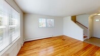 Located at 71 Redden Ave in New London, CT, this 2-bedroom, 2-bathroom home spans three floors, offering a well-organized and functional layout. The main level features a combined kitchen and living area, where warm hardwood floors flow throughout. The living space is filled with natural light from large windows that overlook the surrounding greenery, and a staircase connects the levels seamlessly. The kitchen is outfitted with abundant warm-toned wood cabinetry, ample counter space, a gas range, dishwasher, and full-size refrigerator — providing everything needed for everyday cooking. The upper floors house two bedrooms, each with hardwood flooring and baseboard heating. The primary bedroom includes a spacious sliding-door closet, while the hallway connects the bedrooms to two full bathrooms. The bathrooms feature tile flooring, wood-cabinet vanities, large mirrors, and bright windows that let in natural light. The basement level adds notable value, offering two separate storage areas — one open and expansive with a painted concrete floor, and a second with wire shelving for organized storage — plus a dedicated utility room. Baseboard heating is present throughout the home, ensuring consistent comfort year-round.