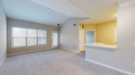 Located at 4330 Point Cypress Blvd in Wesley Chapel, Florida, this single-story residence offers a well-designed, open layout that maximizes both space and functionality. The living area is highlighted by soaring vaulted ceilings that create an airy, expansive atmosphere, complemented by large windows that allow generous natural light to fill the room. Soft carpeting throughout the living and bedroom areas adds warmth and comfort underfoot.

The kitchen is positioned adjacent to the living space in an open-concept configuration, featuring a peninsula counter that serves as both a workspace and a visual divider. Crisp white cabinetry with black hardware, white countertops, a stainless steel sink, and stainless steel appliances — including a range, microwave, and refrigerator — give the kitchen a clean, modern appeal. Track lighting provides focused illumination over the cooking and prep areas.

The bedrooms are generously sized and carpeted, each with windows that invite natural light. The primary bedroom includes walk-in closet space, offering practical storage solutions. The bathroom is well-appointed with a combination tub and shower, a white vanity with matching cabinetry and black hardware, and durable wood-look flooring. The overall design palette of neutral tones throughout creates a cohesive and inviting living environment.