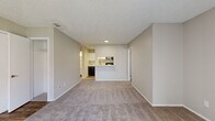 This single-floor, 2-bedroom, 1-bathroom residence offers a practical and comfortable layout designed for efficient everyday living. The open living area is finished with neutral-toned carpet and soft beige walls, creating a clean and inviting atmosphere throughout. Large vertical blinds in the living room allow for adjustable natural light, while a textured ceiling adds a classic touch consistent across all rooms.

The kitchen connects to the living area via a pass-through counter, offering white cabinetry, granite-look laminate countertops, a stainless steel sink, and black appliances, including a range and dishwasher. Wood-look flooring in the kitchen and bathroom provides a durable, easy-to-clean surface in high-traffic areas.

Both bedrooms are carpeted and equipped with ceiling fans and dedicated walk-in closets with built-in shelving, offering generous storage. The primary bedroom provides a comfortable, well-proportioned space suitable for a full furniture arrangement.

The bathroom features a full tub-shower combo with white tile surround, brushed nickel fixtures, and wood-look flooring that ties in with the kitchen aesthetic. The overall design is neutral and move-in ready, making it a functional and versatile living space.