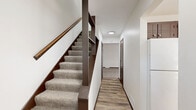 Located at 1652 69th Ave NE in Fridley, Minnesota, this three-bedroom, two-bathroom home is thoughtfully distributed across three floors, offering well-defined living spaces throughout. The main level features a kitchen equipped with dark espresso cabinetry, light granite-style countertops, wood-look plank flooring, and white appliances including a gas range and refrigerator. A dedicated dining room and a carpeted living room round out the main living area, with the living room opening to the outdoors through a sliding glass door framed by vertical blinds. Carpeted staircases with dark wood handrails connect each level, complemented by hallways with wood-look flooring for easy transition between spaces. The upper floor hosts three bedrooms, each featuring neutral carpet, white walls, dark window trim with blinds, and floor vents — including a generously sized primary bedroom. Two full bathrooms serve the home with clean, simple white fixtures. The lower level provides an unfinished basement with a painted concrete floor, exposed wood beam ceiling, and an electrical panel, offering excellent potential for storage or future finishing. Five closets throughout the home ensure ample storage, and a utility room accommodates mechanical systems. Outside, the property features a concrete patio and access to nearby garage parking.