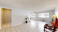 Located at 7500 Laurel Canyon Blvd in Los Angeles, CA, this single-floor, one-bedroom, one-bathroom unit offers a functional and comfortable layout. Light-toned ceramic tile flooring runs throughout the main living areas, contributing to a bright and cohesive feel. The open living room is generously sized, featuring a textured ceiling, a wall-mounted air conditioning unit, and large windows that invite natural light from multiple directions. A ceiling fan provides additional comfort in the living space.

The kitchen is well-appointed with white cabinetry, granite-style countertops, a stainless steel range with overhead microwave, and a full suite of storage including upper shelving. A window above the counter brings in natural light, keeping the space feeling open and airy.

The bedroom is a comfortable size, featuring large-format tile flooring, a ceiling fan, and a wide window with outdoor views. A mirrored sliding-door closet adds both storage and a sense of added depth to the room.

The bathroom includes a tub and shower combination with sliding frosted glass doors, tile surround, a vanity with countertop space, and tile flooring. A connecting hallway ties the rooms together efficiently, completing this practical and well-laid-out Los Angeles residence.