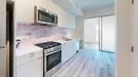 This thoughtfully designed one-bedroom, one-bathroom apartment is located on the fourth floor at 1530 Cassil Pl in the heart of Hollywood, Los Angeles. The unit features light wood-tone laminate flooring throughout, creating a bright and cohesive aesthetic across every room.

The open kitchen is a standout feature, equipped with stainless steel appliances including a gas range, built-in microwave, and dishwasher. Sleek white cabinetry extends to the ceiling for ample storage, while a warm rose-toned subway tile backsplash adds a distinctive design element. A built-in desk area adjacent to the kitchen provides a convenient workspace. A frosted glass sliding door connects the kitchen to the living area, allowing for flexible, open-concept living.

The living and bedroom area is clean and airy, with crisp white walls, track lighting, and a smart entry system at the front door. The layout is efficiently designed to maximize usable space.

The bathroom is finished with polished marble-style floor tiles and features a glass-enclosed walk-in shower accented by rich cobalt blue handmade-style brick tiles, lending a bold, modern touch. White cabinetry and fixtures complete the clean, contemporary look. This apartment offers a well-appointed urban living experience in a prime Los Angeles location.