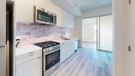 This thoughtfully designed one-bedroom, one-bathroom apartment is located on the fourth floor at 1530 Cassil Pl in the heart of Hollywood, Los Angeles. The unit features light wood-tone laminate flooring throughout, creating a bright and cohesive aesthetic across every room.

The open kitchen is a standout feature, equipped with stainless steel appliances including a gas range, built-in microwave, and dishwasher. Sleek white cabinetry extends to the ceiling for ample storage, while a warm rose-toned subway tile backsplash adds a distinctive design element. A built-in desk area adjacent to the kitchen provides a convenient workspace. A frosted glass sliding door connects the kitchen to the living area, allowing for flexible, open-concept living.

The living and bedroom area is clean and airy, with crisp white walls, track lighting, and a smart entry system at the front door. The layout is efficiently designed to maximize usable space.

The bathroom is finished with polished marble-style floor tiles and features a glass-enclosed walk-in shower accented by rich cobalt blue handmade-style brick tiles, lending a bold, modern touch. White cabinetry and fixtures complete the clean, contemporary look. This apartment offers a well-appointed urban living experience in a prime Los Angeles location.