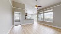 This single-floor residence offers a thoughtfully designed open-concept layout that seamlessly connects the living, dining, and kitchen areas. The main living space is anchored by soaring vaulted ceilings, a ceiling fan, and an abundance of natural light streaming through large windows with arched accents and slatted blinds. Light-toned hardwood-style flooring flows throughout the main areas, enhancing the airy, spacious feel.

The kitchen is a standout feature, showcasing raised-panel gray cabinetry, granite countertops, a classic white subway tile backsplash, and a full suite of stainless steel appliances including a refrigerator, range, microwave, and dishwasher. A peninsula with a granite overhang provides additional prep space and casual seating while maintaining the open sightlines to the living area.

The bedrooms are finished with plush carpeting and ceiling fans, offering a comfortable retreat. Each room benefits from natural light, with one bedroom featuring an arched window. The bathrooms are well-equipped, with the primary bath offering a dual-sink vanity topped with granite, gray cabinetry with brushed nickel hardware, wood-style flooring, and a soaking tub with tile surround. A second full bathroom mirrors the same quality finishes. The neutral color palette throughout creates a clean, cohesive, and welcoming atmosphere.