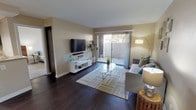 This single-floor residence offers a thoughtfully designed layout that balances comfort and functionality across its living spaces. The living room serves as the heart of the home, featuring rich dark hardwood flooring, warm neutral-toned walls, and a large sliding glass door that floods the space with natural light and provides direct access to a private outdoor patio. A wall-mounted flat-screen TV and a sleek white media console anchor one side of the room, while the open layout allows for a generous seating arrangement.

The kitchen is outfitted with dark espresso cabinetry, light stone countertops, and a full suite of stainless steel appliances including a gas range, built-in microwave, dishwasher, and double sink — offering a clean, modern aesthetic with practical functionality.

The primary bedroom features plush carpeting, a spacious mirrored sliding-door closet, and a bright window with outdoor views. An en-suite bathroom provides a vanity with stone countertops and ample mirror space. A second bedroom, also carpeted, includes its own closet and access to a well-appointed full bathroom. Throughout, the neutral color palette and clean finishes create a cohesive, inviting ambiance suited for everyday living.