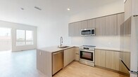 This contemporary 1-bedroom, 1-bathroom residence in San Diego, CA offers a thoughtfully designed open-concept layout with modern finishes throughout. Light wood-style flooring flows seamlessly across the entire unit, complementing the clean white walls and creating a bright, cohesive aesthetic.

The kitchen is a standout feature, equipped with flat-front cabinetry in a warm wood-grain finish, a quartz peninsula with an undermount sink and pull-down faucet, and a full suite of stainless steel appliances including a refrigerator, electric range, over-the-range microwave, and dishwasher. A marble-inspired tile backsplash adds a refined touch.

The living area is generously proportioned, benefiting from large sliding glass doors that open directly onto a private balcony, flooding the space with natural light and offering open urban views of the San Diego skyline. The bedroom is well-sized with large windows that continue to bring in ample daylight and city views.

The bathroom features a light wood-grain vanity with a clean-lined countertop, a full soaking tub with tile surround, and a bright mirror with overhead lighting. The unit's modern design, quality materials, and access to outdoor space make it a well-rounded urban residence.