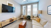 Located at 146 Roberts St in the heart of Asheville, NC, this thoughtfully designed one-bedroom, one-bathroom unit offers a contemporary living experience across a single floor. Polished concrete floors run throughout, lending the space a sleek, modern aesthetic that complements the neutral gray and warm beige color palette.

The open-concept kitchen and living area serves as the centerpiece of the home. The kitchen is well-appointed with two-tone cabinetry — dark lower cabinets paired with light wood upper cabinets — granite countertops, a subway tile backsplash, stainless steel appliances including a French door refrigerator and electric range, and a kitchen island with seating. Pendant lighting adds an elegant finishing touch overhead.

The living room benefits from large windows that invite abundant natural light and features a ceiling fan. Recessed niches on the living room wall add an architectural detail that connects visually to the bedroom beyond.

The bedroom is a calm retreat with elevated ceilings, transom-style windows, a spacious closet, and access to additional storage. A stylish sliding barn door with matte black hardware adds a modern-industrial accent. The unit also includes a dedicated laundry area, a full bathroom, and a hallway connecting all spaces efficiently.