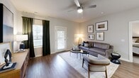 Located at 13100 Margie Ln in Raleigh, NC, this 2-bedroom, 2-bathroom residence offers a thoughtfully designed single-floor layout with a clean, modern aesthetic throughout. The open-concept living and dining area is anchored by rich hardwood-style flooring, neutral gray walls, and a ceiling fan, with natural light streaming in through multiple windows and a door leading to a private balcony. The kitchen is a functional centerpiece, showcasing light wood cabinetry, white subway tile backsplash, quartz countertops, a large island with an undermount sink, pendant lighting, and a full suite of stainless steel appliances including a range, over-the-range microwave, and French door refrigerator. A dedicated pantry provides additional storage. Both bedrooms feature plush carpet, ceiling fans, and ample natural light, with the primary bedroom offering a generous footprint and its own en-suite bathroom. The primary bath includes a glass-enclosed walk-in shower with white subway tile, while the second bath features a tub-shower combination with matching tile. A dedicated laundry room houses full-size washer and dryer units. Three closets, a utility room, and additional storage space round out this well-organized Raleigh residence.