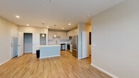 This single-floor residence offers a thoughtfully designed open-concept layout with a seamless flow between the kitchen and living areas. The kitchen serves as a central highlight, featuring white shaker-style cabinetry, light quartz countertops, a central island with pendant lighting overhead, and a full suite of stainless steel appliances including a refrigerator, range, over-the-range microwave, and dishwasher. Recessed lighting and a light-toned wood-look floor enhance the bright, clean aesthetic throughout the main living area, which also benefits from a ceiling fan and a window overlooking greenery outside.

The bedrooms are finished with plush carpeting and include closet space, with the layout providing a clear separation between living and sleeping areas. Two bathrooms serve the unit: one features a tiled tub-shower combination with a white vanity, while the other offers a glass-enclosed tiled walk-in shower, also paired with a white shaker vanity and light countertop. Neutral tones, clean lines, and consistent finishes throughout give the space a cohesive, modern character well-suited for comfortable everyday living.
