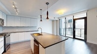 Located in the heart of Midtown Atlanta, this 2-bedroom, 1-bathroom residence offers a thoughtfully designed open layout with modern finishes throughout. Dark hardwood-style flooring flows seamlessly from the entry hallway through the living areas, creating a cohesive and polished aesthetic.

The open-concept kitchen is a standout feature, showcasing white flat-panel cabinetry, subway tile backsplash, a large center island with a dark quartz countertop and integrated gold-toned sink, and sculptural pendant lighting. Floor-to-ceiling sliding glass doors in the living area flood the space with natural light and provide direct access to a private balcony with city views.

Both bedrooms are well-proportioned, each featuring large windows or floor-to-ceiling glass panels that frame sweeping views of the Atlanta skyline. The primary bedroom is a comfortable size with a ceiling fan and abundant natural light. A dedicated closet and additional hallway storage add practical functionality.

The bathroom is finished in crisp white marble-style tile, featuring both a soaking tub and a separate glass-enclosed shower, along with a dual-zone layout that enhances privacy. A clean hallway connects all rooms efficiently. The overall ambiance is bright, contemporary, and urban.