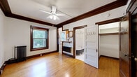 Located at 443 Ashland Ave in Saint Paul, Minnesota, this compact studio unit showcases timeless architectural character through its rich, dark-stained wood trim, crown molding, and warm hardwood floors that run throughout the space. The living area is bright and inviting, featuring a ceiling fan with light fixture, a classic cast-iron radiator for heating, and a wood-framed window that lets in natural light and offers views of the surrounding greenery. A built-in shelving unit adds functional storage and a touch of vintage charm to the room. The kitchen is efficiently designed with warm wood cabinetry, granite countertops, a stainless steel sink, and a gas range, providing all essential cooking amenities. The bathroom is a standout highlight, preserving classic details including a freestanding clawfoot bathtub with an overhead shower, classic penny-tile flooring, a pedestal sink, and a cast-iron radiator — all set against a clean, white palette. A dedicated closet with built-in hooks provides convenient storage. Throughout the unit, the consistent use of dark wood trim, white walls, and natural materials creates a cohesive, character-rich ambiance that reflects the historic charm of the Saint Paul neighborhood.