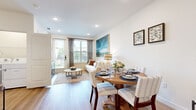 This thoughtfully designed single-floor residence offers a seamless open-concept layout that connects the living, dining, and kitchen areas into one cohesive and functional space. Light hardwood floors run throughout, lending warmth and continuity across every room.

The kitchen is a standout feature, showcasing white shaker cabinetry, granite countertops, stainless steel appliances, and a central island with bar seating illuminated by pendant lighting — ideal for both cooking and casual dining. Adjacent to the kitchen, the dedicated dining area comfortably accommodates a full-sized table and flows naturally into the living room, which is brightened by large windows and a glass door that invite generous natural light and outdoor views.

The bedroom is a tranquil retreat, featuring large windows with blinds and drapery, a ceiling fan, and a walk-in closet outfitted with built-in shelving and hanging rods for well-organized storage. The bathroom continues the home's clean aesthetic with white cabinetry, granite countertops, a framed mirror, and a tub-shower combination with subway tile surround. In-unit laundry is also accessible, adding everyday convenience. Throughout, the space maintains a bright, neutral palette that creates a calm and livable atmosphere.