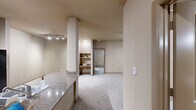 Located on Vance Jackson Road in San Antonio, Texas, this single-floor residence offers a well-designed layout with two bedrooms, two bathrooms, and a generous overall footprint. The kitchen is fitted with light wood cabinetry, granite-style countertops, a breakfast bar peninsula, and black appliances including a refrigerator, range, and dishwasher. Light hardwood-style flooring runs through the kitchen, transitioning to plush carpet in the living and bedroom areas. The primary bedroom is a spacious retreat featuring a ceiling fan, a large window that invites natural light, and access to a walk-in closet outfitted with dual hanging rods and multiple shelving tiers for ample storage. A second walk-in closet mirrors this practical design. The primary bathroom is notably expansive, featuring a double-sink vanity with warm wood cabinetry and stone-look countertops, tile flooring, and a shower-tub combination. The second bathroom offers a single vanity with matching finishes and a tub-shower combo. Additional highlights include a dedicated in-unit laundry area housing a full-size washer, a private balcony, and neutral warm-tone walls throughout that lend a cohesive, inviting ambiance across the entire space.