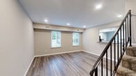 Located at 201 Kimgstowne Rd in Newport News, VA, this two-story, 2-bedroom, 2-bathroom home is thoughtfully laid out across two well-proportioned floors. The main level features an open living area with light-toned luxury vinyl plank flooring, neutral walls, and recessed lighting that creates a bright, welcoming atmosphere. A staircase with a sleek black metal railing connects the two floors. The kitchen is equipped with a glass-top electric range, an over-the-range microwave, stone-look countertops, white cabinetry, and a window with outdoor views, allowing natural light to fill the space. The upper level hosts both bedrooms, each carpeted and painted in soft neutral tones with windows that let in natural light. The primary bedroom is a comfortable size and is accompanied by a dedicated bathroom featuring a white vanity with ample counter space and a full walk-in shower. A second full bathroom serves the additional bedroom. The home also includes a den, multiple closets throughout — offering generous storage — and two hallways connecting the living spaces. The overall design is clean and functional, making efficient use of every square foot across both floors.
