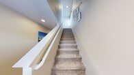 This meticulously designed three-story residence offers 2380 square feet of living space, thoughtfully distributed across three floors. The home boasts three bedrooms, including a generous 190 square foot primary suite, and three full bathrooms, ensuring comfort and privacy for all occupants.

The ground floor, spanning 730 square feet, houses the main living areas. It features an open-concept design integrating the kitchen, dining room, and living room. The kitchen is a highlight, showcasing pristine white cabinetry, stainless steel appliances, and a sleek subway tile backsplash. Adjacent, the dining area accommodates a round table, perfect for intimate meals or entertaining.

The second floor, at 910 square feet, likely contains the bedrooms. The primary bedroom is notably spacious and includes a vanity area. Other bedrooms are well-proportioned, with one featuring built-in storage and a work desk, ideal for a home office or study space.

The 740 square foot basement is finished, offering additional living space. It's currently set up as a recreational area with comfortable seating and ample room for various activities.

Throughout the home, large windows and glass doors allow natural light to flood the spaces, creating a bright and airy atmosphere. The interior design is characterized by a neutral color palette, with occasional pops of color in furnishings and decor. Hardwood and carpeted floors are used throughout, adding warmth and texture to the living spaces.

Additional amenities include a dedicated laundry room with modern appliances and storage solutions, multiple closets for ample storage, and two staircases for easy navigation between floors. The property's thoughtful layout and attention to detail make it an ideal space for comfortable family living.