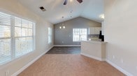 Located at 800 Churchill Downs Dr in Aberdeen, NC, this two-story residence offers a thoughtfully designed layout across two levels. The main living area immediately impresses with soaring vaulted ceilings and ceiling fans that enhance the sense of openness and airflow. Natural light filters through multiple windows fitted with blinds, brightening the neutral-toned interiors throughout.

The open-concept layout connects the carpeted living room to a dedicated dining area, accented by a chandelier beneath the vaulted ceiling. The kitchen features wood-look flooring, white shaker-style cabinetry, light countertops, and a full suite of black appliances, including a refrigerator, electric range, dishwasher, and built-in microwave. A breakfast bar separates the kitchen from the living space.

Bathrooms are finished with wood-look flooring, light countertops, and full tub-shower combinations. One bathroom includes convenient access to a walk-in closet with built-in shelving and rod storage. An additional bathroom offers a dedicated laundry area with washer/dryer hookups.

The upper level is accessed via a staircase with a wood handrail and features a carpeted bedroom with a sloped ceiling and ceiling fan, adding a cozy, tucked-away feel. Throughout the home, clean white trim, neutral wall tones, and consistent finishes create a cohesive and inviting atmosphere.