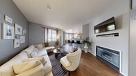 Located in Las Vegas, NV, this well-appointed 2-bedroom, 2-bathroom residence offers a thoughtfully designed single-level layout. The open-concept living, dining, and kitchen area serves as the heart of the home, featuring rich wood-style flooring, a cozy fireplace, and a wall-mounted TV niche in the living room. Large windows allow natural light to fill the space, while access to a private balcony provides an outdoor retreat. The kitchen is equipped with warm wood cabinetry, a breakfast bar with seating, track lighting, and a full suite of appliances. The adjacent dining area offers pleasant outdoor views through generous windows. The primary bedroom is a comfortable retreat with plush carpet, soft neutral tones, and ample natural light from sheer-draped windows. The second bedroom features a distinctive accent wall and carpet flooring. Both bathrooms are finished with clean white fixtures, wood-toned vanity cabinetry, and a tub-shower combination. Two closets provide generous storage throughout, and a dedicated laundry area adds everyday convenience. The overall aesthetic blends modern sensibility with warm, inviting tones, creating a cohesive and functional living environment.