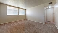 Located at 3000 W Douglas Ave in Wichita, Kansas, this single-floor unit offers a practical and straightforward layout designed for comfortable everyday living. The open floor plan connects the living area to the kitchen, creating a cohesive and functional space. The kitchen is equipped with rich dark-brown cabinetry, a built-in range, a dishwasher, and a sink, all set against light countertops and durable tile flooring. A range hood is integrated into the upper cabinetry, adding to the kitchen's utility. The living and bedroom areas feature wall-to-wall carpet in a warm neutral tone, providing a comfortable underfoot feel throughout. Textured ceilings are present in several rooms, adding a classic architectural detail. Natural light filters into the bedrooms through windows fitted with horizontal blinds, creating a bright yet private atmosphere. The full bathroom includes a tub-shower combination, a toilet, a vanity with storage, and clean tile flooring, offering a complete and well-appointed space. A dedicated walk-in closet with a built-in shelf and hanging rod provides generous storage capacity. The unit's neutral color palette throughout lends itself well to a variety of interior styles and personal touches.