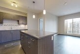 Located at 8515-8525 106A Avenue NW in Edmonton, Alberta, this 2-bedroom, 2-bathroom unit offers a thoughtfully designed open-concept layout across a single floor. The kitchen serves as the centerpiece of the main living area, showcasing dark wood cabinetry, a striking central island with a granite-style countertop, pendant lighting, a mosaic tile backsplash, and a full suite of stainless steel appliances including a refrigerator, stove, microwave, and dishwasher. Rich hardwood-style flooring flows throughout the kitchen and living area, while a large sliding glass door fills the space with natural light and provides outdoor views. Both bedrooms feature plush carpeting, neutral tones, and windows with blinds that bring in additional natural light. The primary bedroom includes a closet with classic panelled doors. Each of the two bathrooms is finished with large-format stone-look tile flooring, dark wood vanities with stone countertops, and a full soaker tub with tile surround. Additional conveniences include in-suite laundry and a dedicated closet. Baseboard heating is present throughout, ensuring year-round comfort in the Edmonton climate.