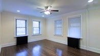 This single-floor space showcases a thoughtfully designed interior that balances classic architectural details with a clean, welcoming aesthetic. The room is anchored by beautifully polished dark hardwood floors that reflect light and lend a sense of warmth and elegance throughout. Crown molding runs along the ceiling perimeter, adding a refined, traditional character to the space.

Natural light is a defining feature, with multiple windows fitted with horizontal blinds positioned along two walls, allowing for flexible light control while maintaining a bright and airy atmosphere. The neutral, soft cream-toned walls complement the dark flooring and create a versatile backdrop suitable for a variety of uses and furnishing styles.

Overhead, a ceiling fan with an integrated light fixture provides both functional illumination and air circulation, contributing to the room's comfort year-round. A recessed light further supplements the lighting options. Baseboard heating units are positioned beneath the windows, ensuring efficient warmth distribution. The generous proportions of the room allow for flexible furniture arrangements, making the space highly adaptable. Overall, the interior exudes a timeless charm, combining classic finishes with practical features to create a comfortable and inviting environment.