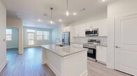 Located at 900 Mountaintop Ave in Gainesville, GA, this well-appointed 1-bedroom, 1-bathroom unit offers a clean, modern aesthetic with a thoughtfully designed single-level floor plan. The open-concept kitchen and living area serves as the heart of the home, anchored by a central island with a granite countertop and integrated sink, illuminated by stylish pendant lighting. White shaker cabinetry, a subway tile backsplash, and a full suite of stainless steel appliances — including a refrigerator with ice maker, electric range, and built-in microwave — complete the kitchen. Wood-look luxury vinyl flooring flows seamlessly throughout the entire space, creating a cohesive and easy-to-maintain finish. The living area offers access to a private balcony through a glass door flanked by large windows that invite abundant natural light. The bedroom is comfortably sized, featuring a ceiling fan, a broad window with outdoor views, and direct access to a spacious walk-in closet outfitted with wire shelving on multiple walls. The bathroom includes a double-sink vanity with granite countertops, a large mirror with overhead lighting, and a soaking tub with a tiled surround. Neutral tones and clean lines throughout give the space a bright, move-in-ready appeal.