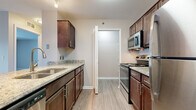 This single-floor residence in Fenton, Michigan offers a thoughtfully designed open-concept layout that seamlessly connects the main living areas. Light wood-style luxury vinyl plank flooring flows throughout the kitchen and living spaces, while plush neutral carpeting adds comfort to the bedrooms and living room.

The kitchen is outfitted with rich dark wood cabinetry, granite-style countertops, a peninsula with a sink, and a full suite of stainless steel appliances, including a range, microwave, and refrigerator. The peninsula provides a natural divider between the kitchen and the open living area, which features a sliding glass door that invites natural light and provides outdoor views.

Both bedrooms are generously sized with soft carpeting and ample closet space, including double closets in one bedroom. The two full bathrooms mirror each other in design, each featuring wood-toned cabinetry with granite countertops, a tub-shower combination with a curved curtain rod, and wood-style vinyl flooring.

A dedicated in-unit laundry area accommodates a full-sized washer and dryer. The overall aesthetic is clean, neutral, and move-in ready throughout.
