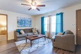 This single-floor residence offers a thoughtfully designed layout that connects the main living areas in a practical and comfortable flow. The living room serves as the central gathering space, featuring dark hardwood-style flooring, a ceiling fan with light fixture, and large windows dressed with teal and neutral curtains that allow generous natural light to fill the room. A plush area rug anchors the seating arrangement, complemented by wall art that adds a touch of color and personality.

Adjacent to the living room, the dining area accommodates a four-seat wooden dining table beneath a pendant light fixture, with a decorative wall mirror and framed artwork enhancing the space. A breakfast bar provides additional seating and connects the dining area to the galley-style kitchen, which is lined with rich wood cabinetry, white countertops, and black appliances including a range, dishwasher, and refrigerator.

Both bedrooms feature plush carpeting and ample closet space, with at least one offering a walk-in closet. The textured ceilings and ceiling fans are consistent throughout. Two bathrooms include wood-toned vanity cabinetry, shower-tub combinations, and overhead storage, providing functional and well-organized spaces throughout the residence.