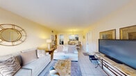 This single-floor residence offers a cohesive, open layout that connects the living, dining, and kitchen areas in a comfortable, functional flow. The living room is finished with light ceramic tile flooring and warm cream-toned walls, creating a bright and inviting atmosphere. A sliding glass door leads directly to a private outdoor patio, allowing natural light to fill the space and providing easy indoor-outdoor access.

Adjacent to the living area, a dedicated dining space features a round granite-topped table beneath a pendant light fixture, with a pass-through window connecting it to the kitchen. The kitchen is efficiently designed with white cabinetry, granite countertops, tile flooring, and black appliances including a range and dishwasher.

The bedroom is a well-proportioned retreat with wood-style plank flooring, a ceiling fan, and a window that allows natural light in. It includes a spacious walk-in closet outfitted with wire shelving and hanging rods, providing generous storage. The full bathroom features tile-surround tub and shower combination, a white vanity with granite countertop, and coordinating tile flooring, completing the space with a clean, polished finish.