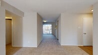 This single-floor residence offers a thoughtfully arranged layout with distinct living, kitchen, bedroom, and bathroom areas. The living room serves as a central gathering space, highlighted by a striking white brick fireplace flanked by windows that allow natural light to fill the room. Plush carpeting runs throughout the living and bedroom areas, contributing to a warm, comfortable atmosphere.

The galley-style kitchen is well-appointed with white cabinetry, light stone-look countertops, a subway tile backsplash, a double basin sink, a dishwasher, and a range. A window at the end of the kitchen brings in additional daylight, and wood-look flooring provides a clean, practical surface underfoot.

The bedrooms are generously sized, each featuring ceiling fans, plush carpeting, and windows fitted with blinds for light control and privacy. A hallway connects the living areas to the private quarters, with wall sconces providing ambient corridor lighting.

Two bathrooms serve the unit: one featuring a tub-shower combination with tile surround and white cabinetry, and a second with a sliding glass-door shower enclosure and stone-look countertops. Wood-look flooring completes each bathroom. A sliding glass door in the living area leads to an outdoor view, adding to the overall sense of openness.