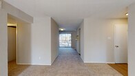 This single-floor residence offers a thoughtfully arranged layout with distinct living, kitchen, bedroom, and bathroom areas. The living room serves as a central gathering space, highlighted by a striking white brick fireplace flanked by windows that allow natural light to fill the room. Plush carpeting runs throughout the living and bedroom areas, contributing to a warm, comfortable atmosphere.

The galley-style kitchen is well-appointed with white cabinetry, light stone-look countertops, a subway tile backsplash, a double basin sink, a dishwasher, and a range. A window at the end of the kitchen brings in additional daylight, and wood-look flooring provides a clean, practical surface underfoot.

The bedrooms are generously sized, each featuring ceiling fans, plush carpeting, and windows fitted with blinds for light control and privacy. A hallway connects the living areas to the private quarters, with wall sconces providing ambient corridor lighting.

Two bathrooms serve the unit: one featuring a tub-shower combination with tile surround and white cabinetry, and a second with a sliding glass-door shower enclosure and stone-look countertops. Wood-look flooring completes each bathroom. A sliding glass door in the living area leads to an outdoor view, adding to the overall sense of openness.
