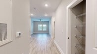This thoughtfully designed one-bedroom, one-bathroom unit offers an efficient and modern living experience across a single floor. Light-toned luxury vinyl plank flooring runs throughout the main living areas, complemented by neutral gray walls and crisp white trim that create a clean, contemporary aesthetic. Recessed lighting and a ceiling fan keep the open living area bright and comfortable, while a window at the far end allows natural light to fill the space.

The kitchen is a standout feature, boasting white shaker-style cabinetry with matte black hardware, granite-look countertops, a subway tile backsplash, and a full suite of stainless steel Whirlpool appliances, including a refrigerator, range, over-the-range microwave, and dishwasher. A black matte faucet adds a stylish finishing touch.

The bedroom offers plush carpeting, dual windows with blinds that invite natural light and outdoor views, and a ceiling fan overhead. It connects directly to a spacious walk-in closet outfitted with wire shelving and carpet flooring, providing ample storage.

The bathroom features wood-look tile flooring, a tub-shower combination with vertical subway tile surround, matte black fixtures, and granite-look countertops. A dedicated laundry room houses a full-size Whirlpool washer and dryer with overhead wire shelving for added convenience.
