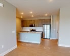 This 1,220-square-foot, single-story apartment in Lawrenceville, GA offers 3 bedrooms and 2 bathrooms thoughtfully designed with modern finishes. The open-concept kitchen and living area serves as the heart of the home, featuring a granite-topped center island with an integrated sink, wood-toned cabinetry, a subway tile backsplash, stainless steel appliances including a refrigerator, electric range, and microwave, and light hardwood-style flooring throughout. Recessed lighting illuminates the space efficiently. The living area extends naturally from the kitchen, offering a ceiling fan and an exterior door providing access to an outdoor area, complemented by large windows that invite abundant natural light. The primary bedroom measures 160 square feet and is appointed with soft carpeting and multiple windows with views to the outdoors. Additional bedrooms are carpeted and well-sized, with easy access to closets. Two walk-in closets feature wire shelving systems for organized storage. The bathrooms include a vanity with dual sinks, wood-toned cabinetry, granite countertops, and hardwood-style flooring. Neutral gray-toned walls throughout the unit create a clean, cohesive aesthetic.