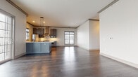 This single-floor residence offers a thoughtfully designed layout that balances open living areas with private spaces. The expansive living room serves as the focal point of the home, showcasing rich dark hardwood floors, elegant crown molding, and a striking floor-to-ceiling stacked stone fireplace. Large windows and sliding glass doors flood the space with natural light and provide access to an outdoor balcony with exterior views.

The kitchen is well-equipped and features gray cabinetry, a decorative tile backsplash, stainless steel appliances including a gas range and refrigerator, a wall-mounted range hood, and a central island. It connects seamlessly to the open living and dining area, making it ideal for entertaining.

The carpeted bedroom areas offer a quieter retreat, with generous windows dressed in blinds that allow for ample natural light. The hallway connects the rooms efficiently, lined with paneled white doors and durable hardwood-style flooring.

Two full bathrooms serve the residence — one featuring a vanity with gray cabinetry and marble-style tile flooring, the other a compact powder-style bath with a pedestal sink. A dedicated laundry room houses a stacked washer and dryer unit alongside a tankless water heater, maximizing functionality within the space. Throughout, neutral tones and quality finishes create a clean, modern aesthetic.