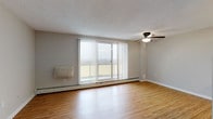 This single-floor residence offers a thoughtfully laid-out living space that balances comfort and functionality. The open-concept living and dining area is finished with warm hardwood flooring and features a ceiling fan with integrated lighting. A large sliding glass door with vertical blinds opens to a private balcony, filling the room with natural light and providing outdoor views. Baseboard heating runs along the perimeter, ensuring year-round comfort.

The kitchen is outfitted with rich dark-espresso cabinetry, granite countertops, a classic white subway tile backsplash, and a full suite of stainless steel appliances including a gas range, over-the-range microwave, and dishwasher. A peninsula counter connects the kitchen to the living area, creating a seamless flow between spaces.

Two generously sized bedrooms feature plush wall-to-wall carpeting, baseboard heating, and windows that allow natural light to filter in. The neutral tones and clean lines of each room create a calm and versatile atmosphere.

The full bathroom is finished with warm beige tile throughout, including a tub and shower combination with a handheld showerhead, complemented by a granite-topped vanity with dark wood cabinetry — consistent with the kitchen's design aesthetic. The overall ambiance of the space is clean, modern, and move-in ready.