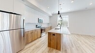 Located at 2340 N 400 W in Provo, Utah, this contemporary two-story residence showcases a clean, modern design throughout. The main level features light-toned hardwood flooring that flows through the open living and kitchen areas. The well-appointed kitchen is a standout, offering wood-grain lower cabinetry paired with crisp white upper cabinets, white quartz countertops, a classic subway tile backsplash, and stainless steel appliances including a range, microwave, and refrigerator. Pendant lighting adds a stylish touch above the counters. A sliding glass door in the living area invites natural light and provides convenient outdoor access. The bathrooms are finished with matching wood-grain vanities, white quartz countertops, matte black hardware, and tub-shower combinations, maintaining a cohesive modern aesthetic. Bedrooms are fitted with plush carpeting and bright windows dressed with blinds, offering views of the surrounding Provo area. A carpeted staircase connects the two levels, and the overall layout is thoughtfully designed to maximize functionality. The consistently neutral white walls, recessed lighting, and coordinated finishes throughout create a bright, clean ambiance well-suited for comfortable everyday living.