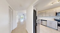 Located at 4101 N Hiatus Rd, Unit 416 in Sunrise, Florida, this three-bedroom, three-bathroom residence offers a thoughtfully organized single-floor layout. The interior is defined by clean white walls, large-format tile flooring throughout, and ceiling fans in the main living areas and bedrooms, contributing to a bright and airy atmosphere well-suited to South Florida's climate.

The living area is generously proportioned, featuring sliding glass doors that open directly onto a private balcony. The balcony offers views of lush tropical palm trees and greenery, providing a serene outdoor retreat. The kitchen includes tile backsplash detailing and cabinetry, with a dining area nearby that benefits from abundant natural light through large windows fitted with vertical blinds.

Each of the three bedrooms is finished with the same light tile flooring and ceiling fans, with windows framing verdant outdoor views. The primary bedroom accesses the balcony via sliding glass doors, enhancing its connection to the outdoors. Storage is addressed through louvered bi-fold closet doors visible on the balcony-adjacent wall.

The three bathrooms maintain a consistent, clean aesthetic with white fixtures, tub-shower combinations, and tile flooring. One bathroom features a pedestal sink, while others include vanity cabinetry with countertops and large mirrors. A hallway and dedicated closet round out the functional layout of this well-appointed Sunrise residence.